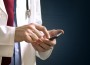 Male doctor in white coat is using a modern smartphone device with tocuh screen.